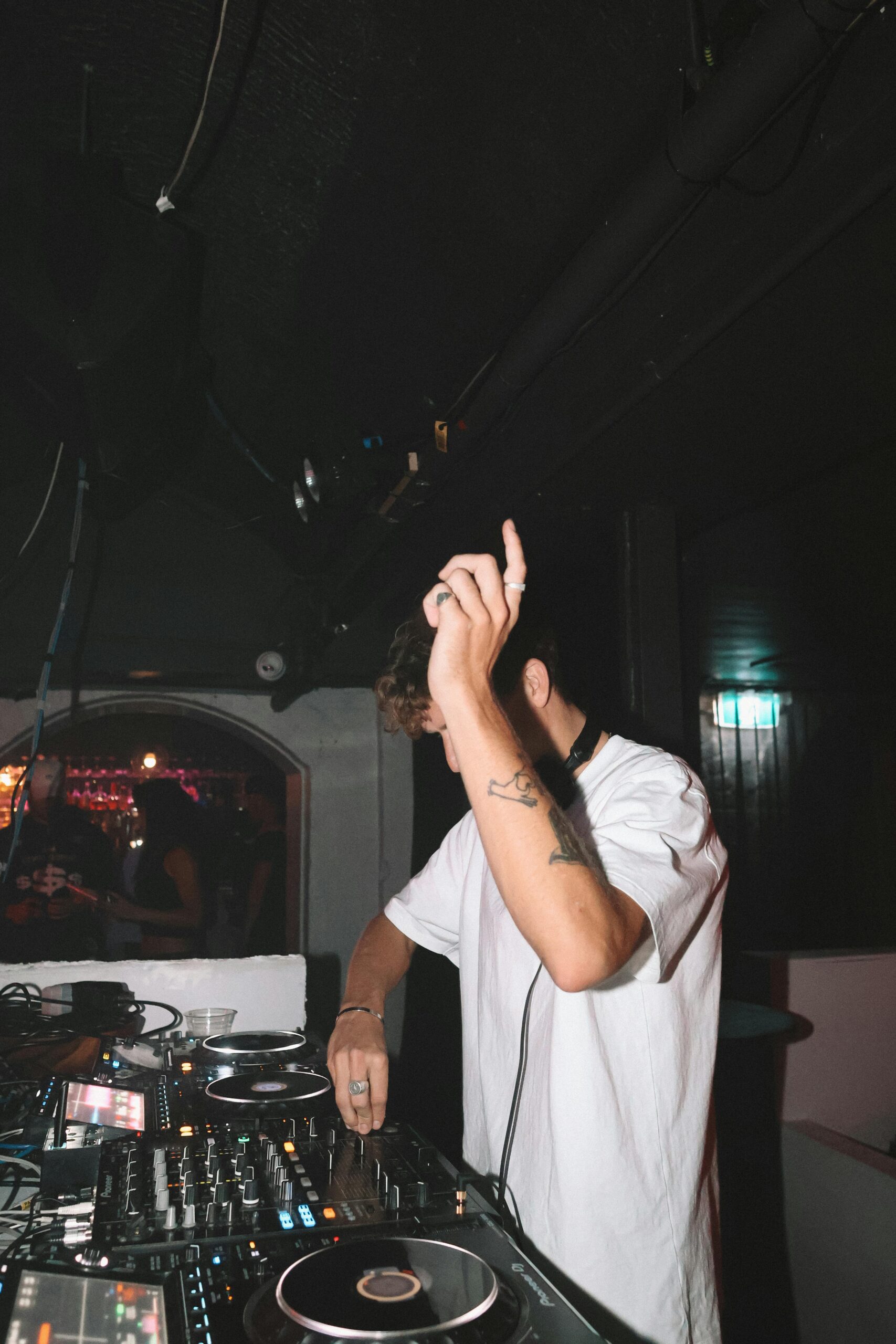 our-services-03 Energetic DJ spinning tracks in a lively club with flashing lights and a vibrant crowd.