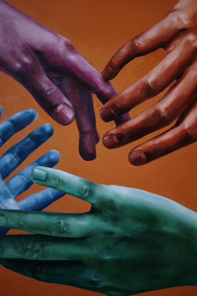 Artistic portrayal of multicolored hands on a vibrant orange background, symbolizing unity and diversity.